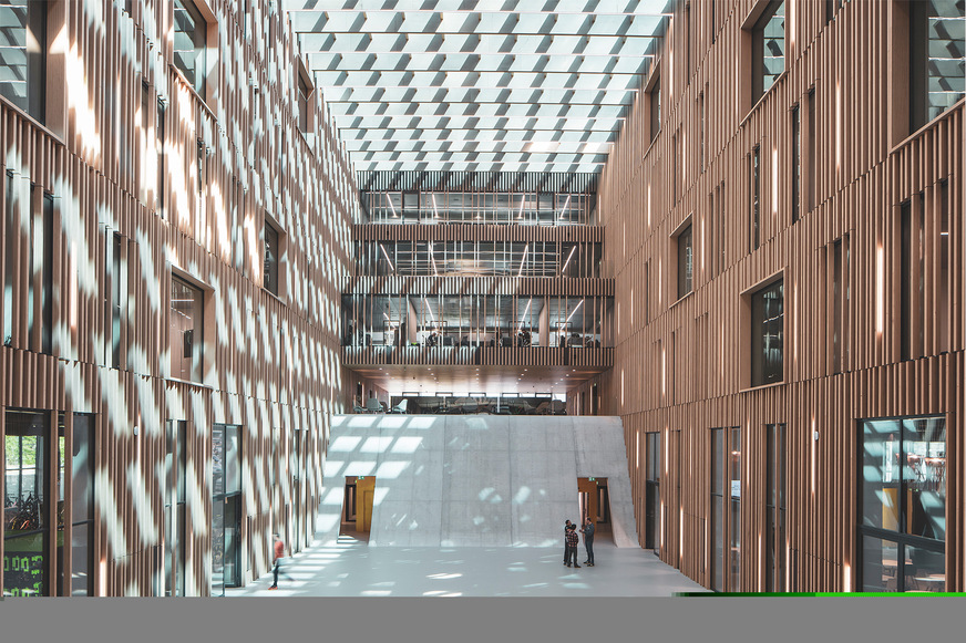 Spannende Licht- und Schattenspiele durch einfallendes Tageslicht und strukturierte Holzlamellen im gebäudehohen