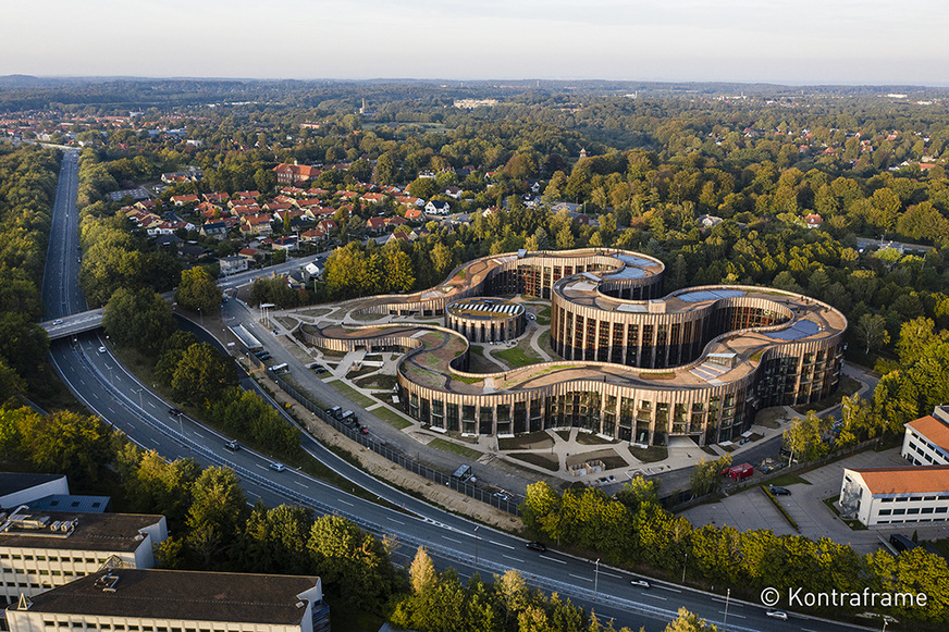 Bei dem BaseCamp Lyngby Gebäude findet sich auf dem Gründach eine Parklandschaft. Die Fassaden erinnern durch die vertikale Anordnung der Paneele in drei Eichenholztönen sowie der Fensterbänder an Bäume und Wälder.