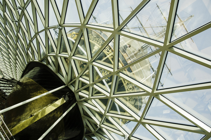 Eine filigrane Dach- und Fassadenkonstruktion umhüllt den Rumpf der Cutty Sark und überdacht so den äußeren Besucherbereich des Museumsschiffs am Ufer der Themse.