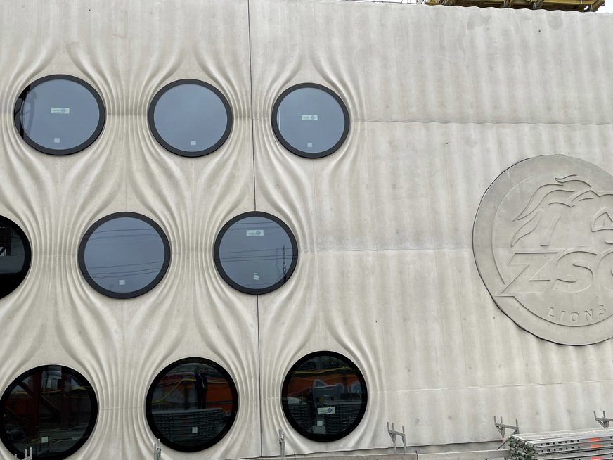 Die filigrane Ortbetonstruktur der Nord- und Süd­seite erzeugt den Eindruck eines textilen Vorhang , der sich um die kreisförmigen Fenster legt, die 2,0 m messen.