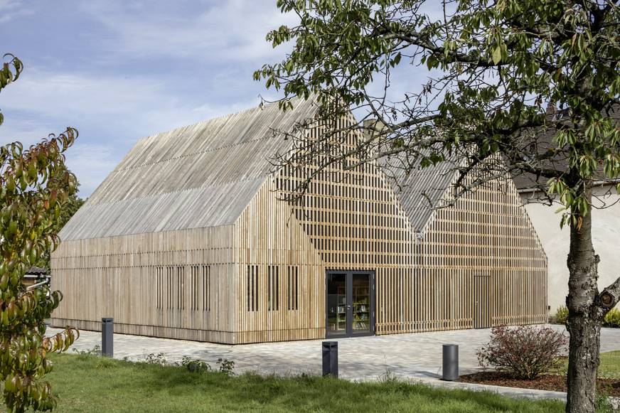 Spektakulär in Szene gesetzt. Von der Form her den Hofgebäuden des 18. Jahrhunderts nachempfunden, sind beide Neubauten komplett mit Eschenlatten verschalt. Semco Energy-Gläser sorgen in der Fassade dahinter für den Klimaschutz.