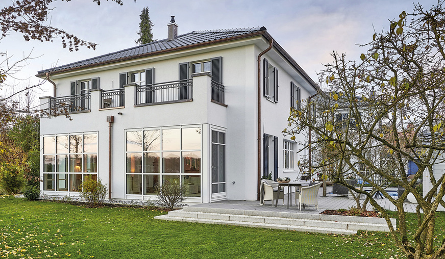 Ausdrucksstark zeigen sich bei dieser Villa im Landhausstil ein Erker sowie teils bodentiefe Sprossenfenster und dunkle Klappläden.