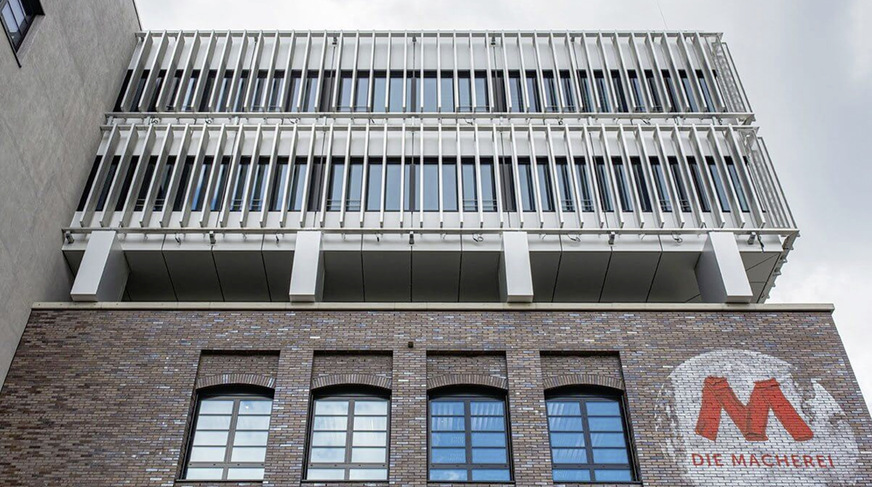 Die Zweiteilung der Architektur mischt Alt und Neu: Hinterlüftete Ziegelfassade die an klassische Industriearchitekturen erinnert, metallene Elementfassade und außen­liegende Sonnenschutzlamellen für Fortschritt und Zukunft.