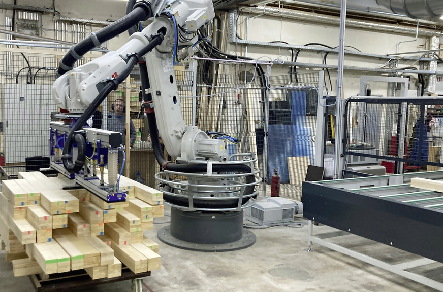 Ein Roboter der Maschinenfabrik Springer erledigt den Abstapelvorgang und die Zuführung auf die ­Kapphobel­linie vor der Conturex-Systemanlage.