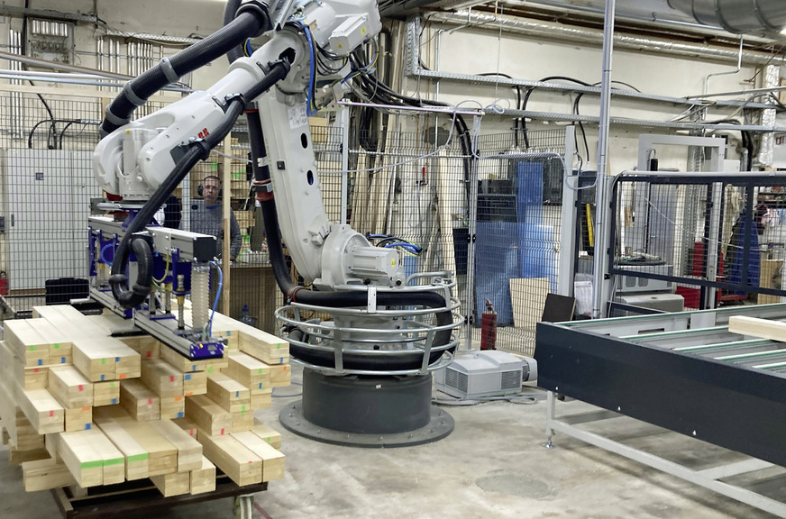 Ein Roboter der Maschinenfabrik Springer erledigt den Abstapelvorgang und die Zuführung auf die Kapphobellinie vor der Conturex-Systemanlage.