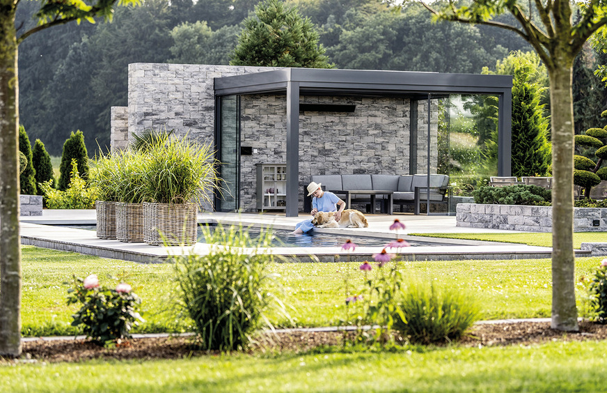 Grün, soweit das Auge reicht. Haus und Garten liegen in einem Naturschutz­gebiet. Das Acubis wurde hier an eine Steinmauer aus gebrochenem Betonstein angebaut, kann jedoch auch als freistehendes Glashaus realisiert werden.