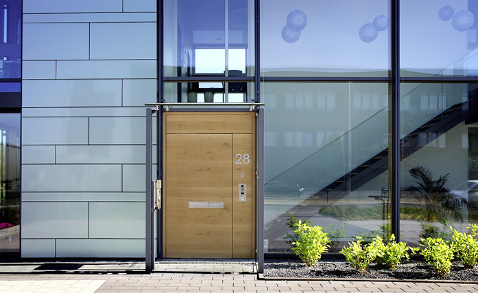 Die Haustür aus Eiche querfurniert mit Fingerprint-Zutritts­system und den flächenbündig eingearbeiteten Komponenten aus Edelstahl verbindet authentisches Design mit zukunftsweisender Technik.