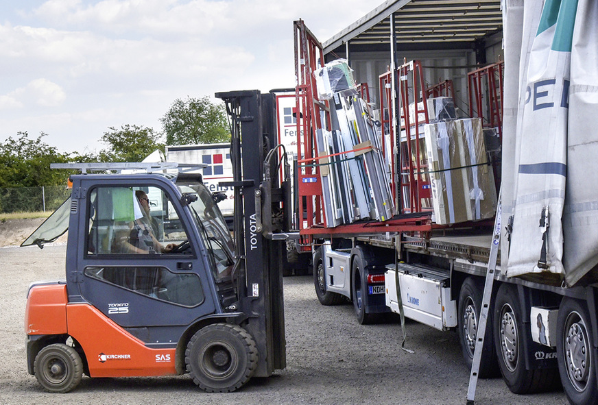 Fertigprodukte, die im Logistikzentrum zwischengelagert waren, werden zur Auslieferung an den Kunden verladen. Die Gabelstapler sind zur perfekten Orientierung des Staplerfahrers mit Notebooks ausgestattet.