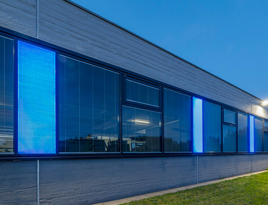 Highlight: Zwischen den Fensterbereichen befinden sich LEDscreen Fassadenpanels, die in der Nacht in blau, das heißt in der Firmenfarbe leuchten.