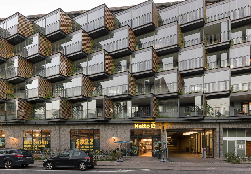 Im dänischen Frederiksberg wurde die Fassade eines Wohnungsbaus aus den 1960er Jahren saniert und in diesem Zuge mit aufgefächerten Kuben erweitert. Die gewonnene Fläche lässt sich von den Bewohnern als erweiterter Wohnraum nutzen.