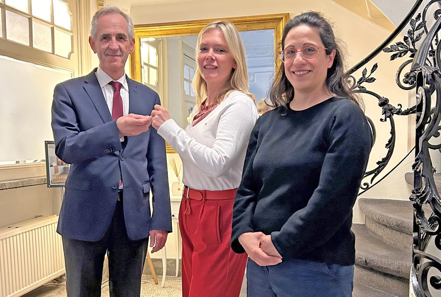 Gerald Feigenbutz (Strategischer Berater) begrüßt die neue Geschäftsführerin Elena Vyboldina in Brüssel und übergibt ihr die Büroschlüssel. Rechts im Bild: Die technische Referentin Laura Espadas Murillo.