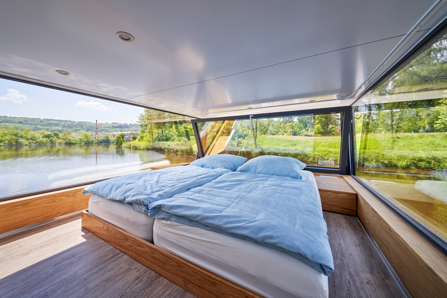 Der obere Schlafbereich ist ein besonderes Highlight des Hausbootes: Hier kann man mit einem Rundumblick in den Tag starten, mit Blick aufs Wasser. Zum Lüften wird das Fenster einfach nach innen gekippt.