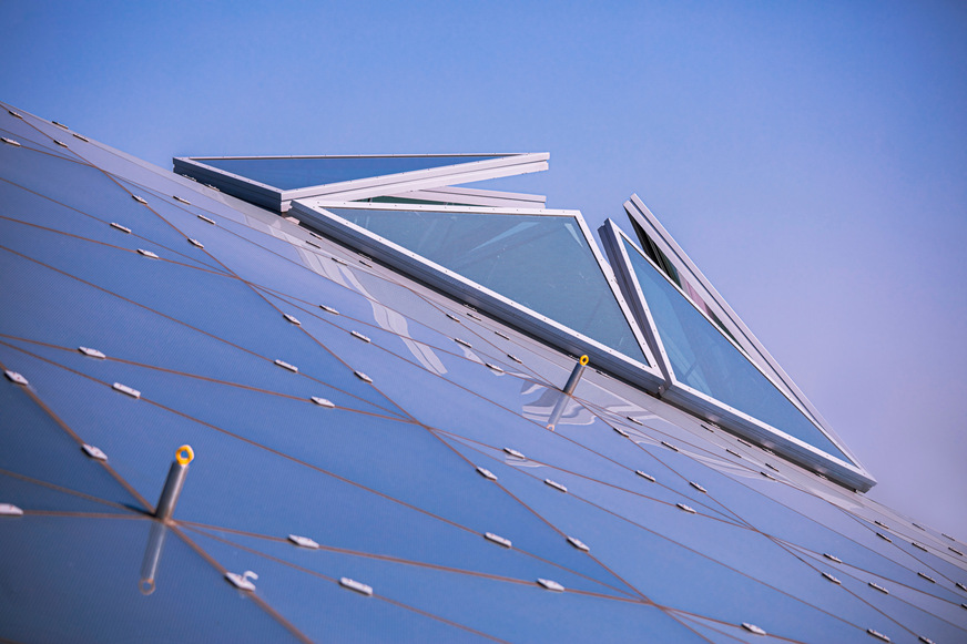 Das 1400 m2 große Freiformdach hat Fassadenbauer Gartner aus 549 drei- und viereckigen Elementen konstruiert, die mit einer komplexen Schraublösung verbunden sind. 24 Elemente öffnen sich zum Rauch- und Wärmeabzug tulpenförmig.