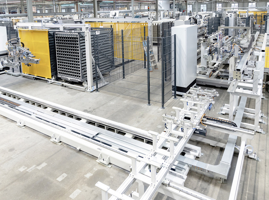 Die Stahlprofile stehen bereit. Positioniert und fein ausgerichtet in den 160 ­Kassetten der Fachwagen. Gezielt greift sich hier der Roboterarm des ­Schirmer Bearbeitungszentrums eines heraus, dreht es bei Bedarf und vermisst es. „Einzig am Markt“: Der automatische Stahleinschub. Hier findet jedes Stahlprofil exakt sein passendes PVC-Pendant.