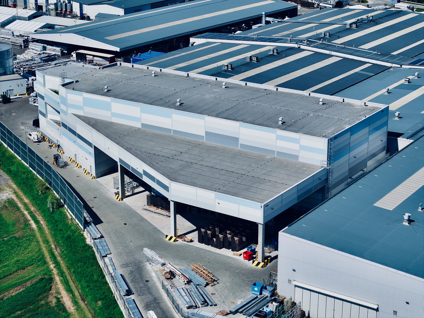 Das neue vollautomatisierte Hochregallager (Gebäudeteil im Vordergrund) mit einem Fassungsvermögen von 29.557,8 m³ bietet Platz für bis zu 1.800 Spezialpaletten.