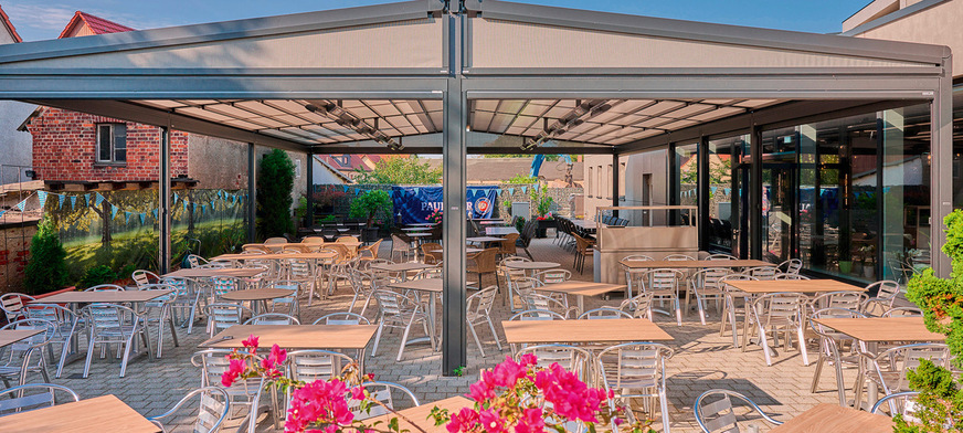 Als freistehendes System sind die pergola stretch an der „markilux syncra“ befestigt. Zusätzliche Dreiecksmarkisen, die an den Außenseiten montiert sind, ­sowie Vertikalmarkisen bieten Schutz vor Wind und leichtem Regen.﻿