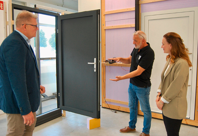 Leiter Produktmanagement Thomas Ochsenreither von Groke mit Marcus Müller (l.), Leitung Vertrieb, und Verena Schilling, Vertriebsassistenz, von der Gargiulo GmbH an der Klimakammer des Herstellers von Aluminium Hauseingangstüren. An der Haustüre links ist unten das zugelieferte Unterbauprofil Insufox aus wärmedämmendem PET-Schaum erkennbar.