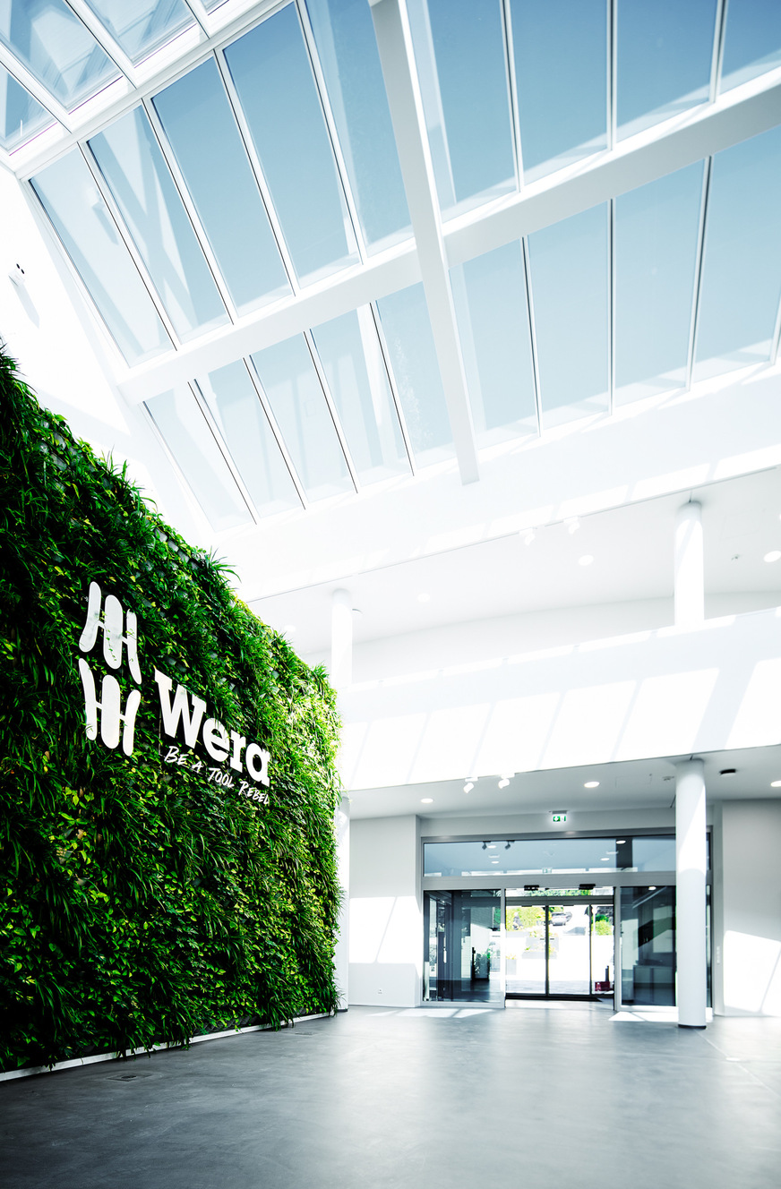 Besucher werden im lichtdurchfluteten Eingangsbereich von einer einladenden Greenwall begrüßt.