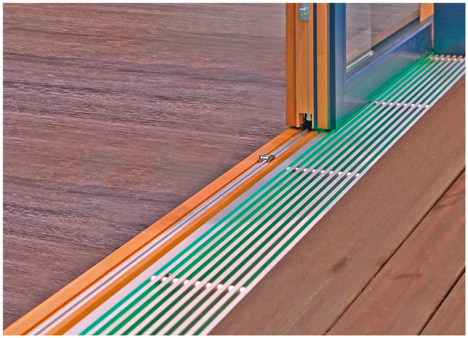 Die Nullbarriere-Schwelle, bei der die Laufschiene in das Bodenprofil eingelassen ist, schafft einen eleganten, bodenbündigen Übergang. Eine integrierte Lichtleiste sorgt für stimmungsvolle Akzente im Raum.