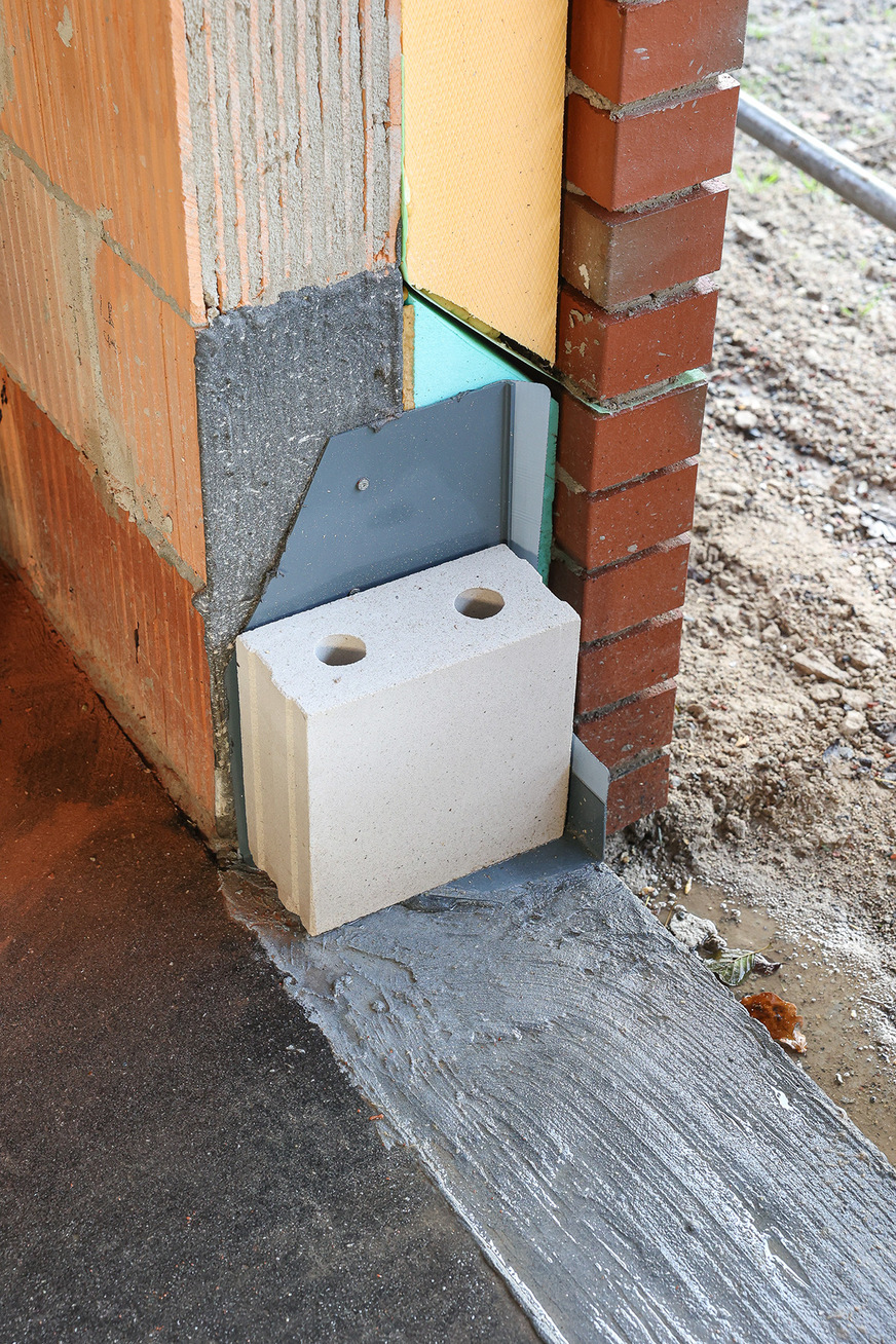 Schutz der Fensterecke während der Bauphase mittels Stein.