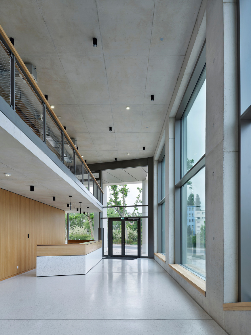 Der Eingang mit dem Foyer befindet sich an der polygonalen Südspitze. Darüber bieten die Konferenzräume mit ihren großflächigen Panoramafenstern einen weiten Ausblick auf die Spree und die Stadt.
