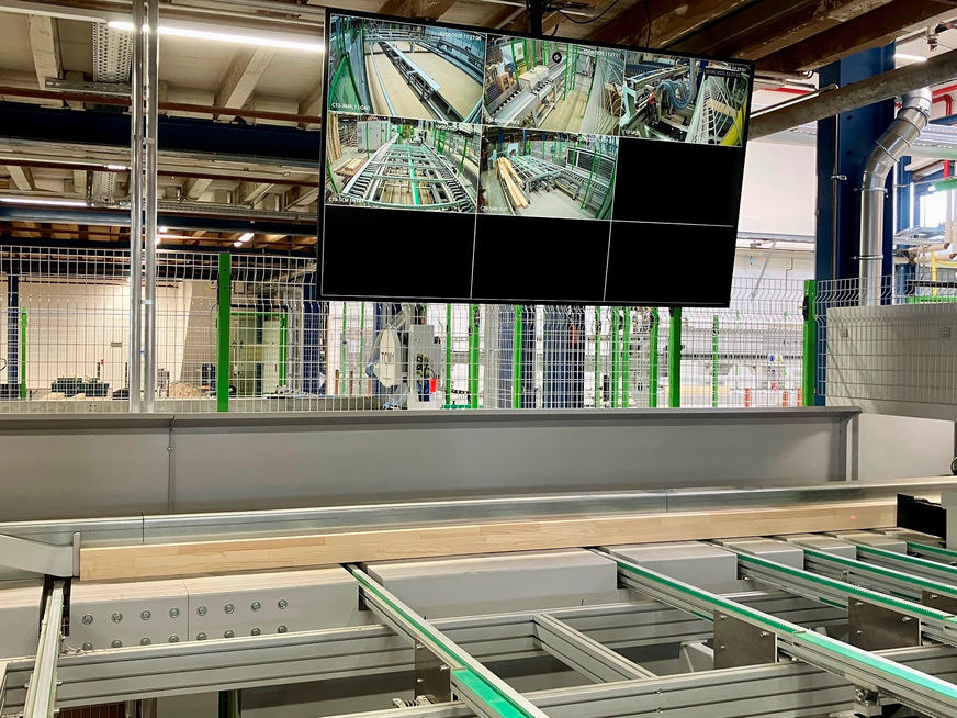 Das Auflegen: Die Rastermaße und 6 m langen keilgezinkten Fensterkanteln werden zur Prüfung vermessen und dann verschnittoptimiert gekappt. Der Bildschirm zeigt lediglich 5 der insgesamt 23 (!) zur permanenten Qualitätskontrolle in der Anlage verbauten Kameras.