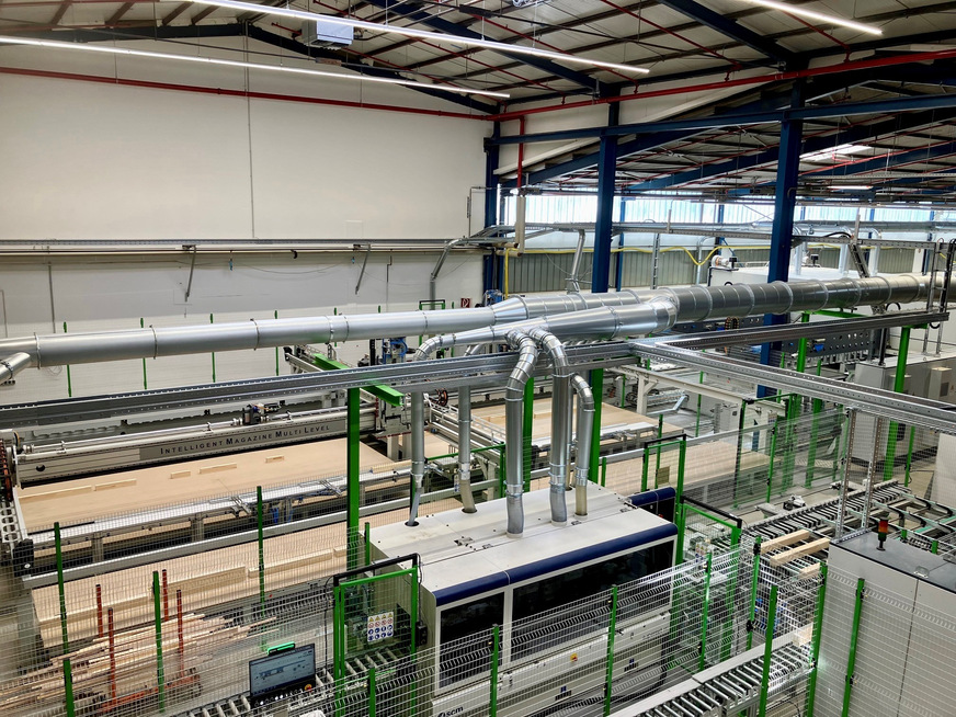 Unten zu sehen ist der SCM Hobelautomat mit 7 Spindeln, wo die Kanteln ausgehobelt und die Glasleistenrohlinge ausgetrennt werden. Auf der anderen Seite befinden sich die erwähnten Pufferräume: Die Intelligent Magazine Multi-Level (IMML) werden zur Vermeidung von Leerlaufzeiten wechselseitig bestückt.