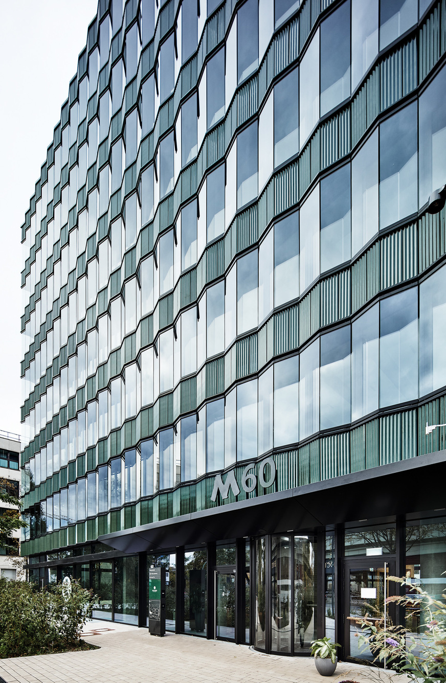 Die Fassade des M60 kombiniert farbige Flächen, Naturmaterialien und Glas zu einer kontrastreichen, eleganten Erscheinung mit variierenden Transparenz- und Reflexionsgraden.
