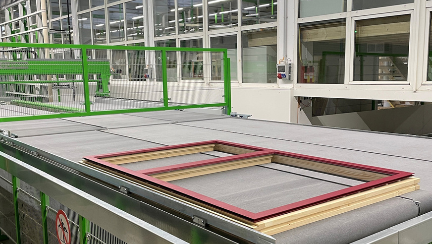 Passgenau vorbereitet: Vorgefertigte Aluschalen werden automatisch zugeführt, händisch am Auflageplatz auf den Rahmen gelegt und an einer Ecke sicher fixiert. Anschließend gelangt er automatisch zur Wendestation, die den Rahmen von der Innenseite auf die Außenseite dreht.