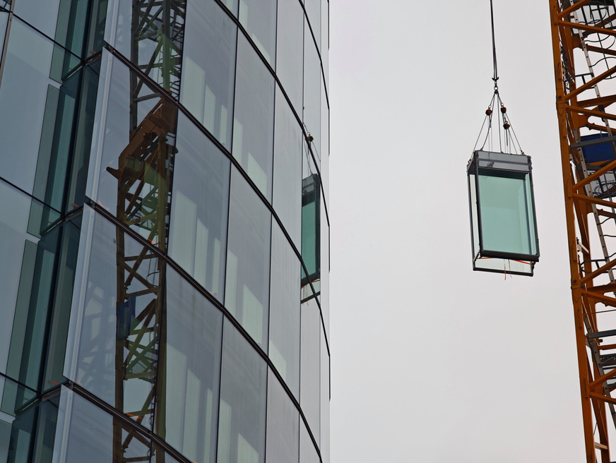 Präzise Vorfertigung für die Gebäudeform: Am A2A Life Tower wird ein verglastes Fassadenelement mit einem Kran in Position gehoben. Focchi entwickelte die modulare Fassade speziell für die Geometrie des Turms, die sich über die Höhe des Gebäudes hinweg verändert.&nbsp;