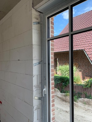 Richtig: Sehr gut ist hier zu erkennen, wie die Montagekonsolen der in der Dämmebene sitzenden Fenstertür im Mauerwerk befestigt sind und somit für einen sicheren Sitz des Elements sorgen.