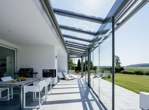 Die Terrasse hat eine gläserne Überdachung von Solarlux erhalten. Die seitliche Verglasung ist schnell aufge­schoben und erlaubt dank der schmalen Führungsschiene einen schwellenlosen Übergang ins Freie.