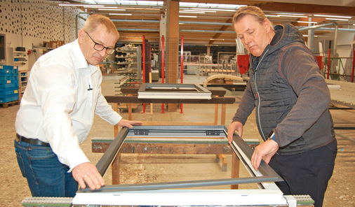 Hubert Hilbring (li.), Produktmanagement und Programmierung, sowie Jürgen Venhaus clipsen den Aluminiumrahmen auf das moderne Kunststofffenster.