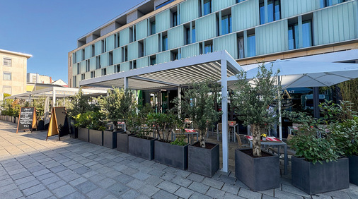 Die Lamellendächer Alba von Corradi wurden in zwei Blöcken 18 × 4 m und 8 × 4 m als gekoppelte Anlagen entlang der Fassade ausgeführt.