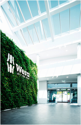 Besucher werden im hellen Foyer von einem einladenden Greenwall begrüßt.