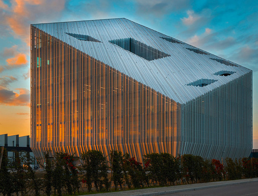 Im Osten und Süden sind Fassade und Schrägdach mit maßgefertigten, gefalzten Elementen aus Aluminium-Gewebe bekleidet.