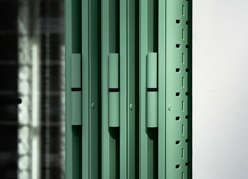 Um die natürliche Atmosphäre des Innenhofs aufzunehmen, wurden die Faltläden in einem zurückhaltenden Lindgrün (NCS S 2020-G10Y) ausgeführt. Gemeinsam bilden Fassaden und Begrünung einen Gegenpol zur hohen urbanen Verdichtung.