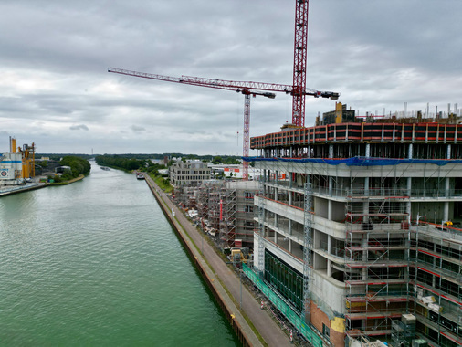 Am Dreieckshafen in Münster entsteht die Ideenwerft als Landmark mit einem 17-geschossigen Büroturm mit 21.000 Quadratmeter (im Vordergrund) und fünf umgebenden, dreigeschossigen Flachbauten am Ufer des Dortmund-Ems-Kanals.