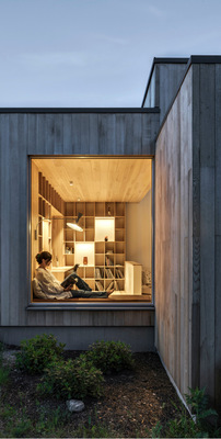 Bauherrin Katarina an ihrem Lieblingsplatz in der Bibliothek. Das große Fenster holt die Natur ins Haus – ein Gestaltungsprinzip, das sich durch das ganze Haus zieht.