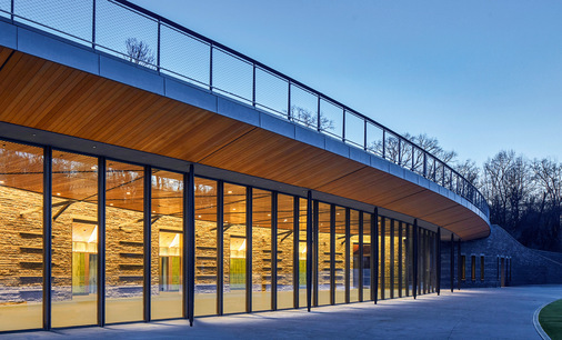 23 maßgefertigte Pivot Drehflügeltüren von Keller minimal windows laufen entlang der konvexen Fassade.