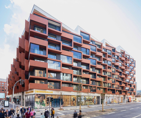 Die Fassade ist geprägt durch eine klare horizontale Gliederung, abgetreppte Terrassen und die ­Materialität des durchgefärbten roten Sichtbetons.