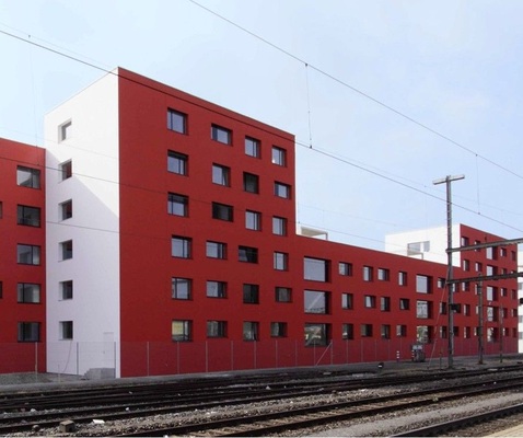Die Nord-Fassade ist in Rot gehalten<br />Das ist die ­Farbe der Bahn. Eingebaut wurden Fensterelemente mit dunklen Profilen und Schallschutzgläsern.