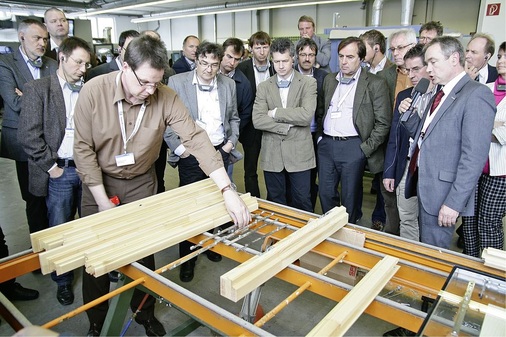 Einzelteilfertigung auf dem Prüfstand — Roland Schöler (mit Mikrofon, ­leitender Produktmanager Siegenia-Aubi KG) erläutert auf der ift-Holzfenstertagung die ­Beschlagmontage am losen Stab.