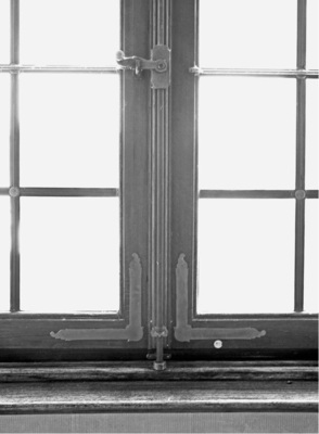 Eine Triebstangenverriegelung, bei der die zweigeteilte Stange in Metallringe am Fensterrahmen greift.