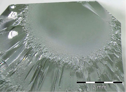 Bruchspiegel an der Glaskante. ­Größe und Radius der glänzenden Fläche ­lassen auf die einwirkende Bruch­energie schließen. Diese lässt sich sehr genau berechnen. In diesem Fall lag die Temperaturdifferenz bei rund 80K.