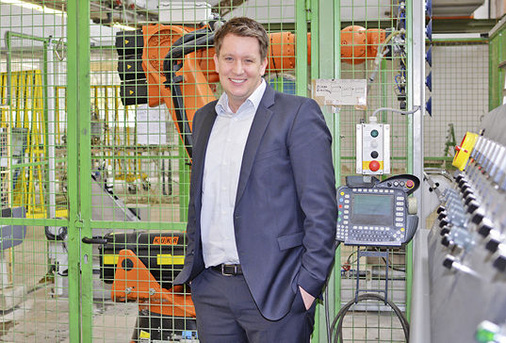 
Glasprofi-Geschäftsführer Achim Haag in der Werkstatt des Unternehmens, im Hintergrund ein Roboter.
