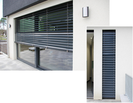 
Elektrisch gesteuerter Sonnenschutz mit langen Lamellen vor der großflächig verglasten, automatisch öffnenden Schiebetür an der Terrasse. Im geschlossenen Zustand wirken die Sonnenschutzlamellen wie ein zusätzlicher Einbruchschutz.
