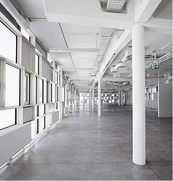 



Auch im Inneren setzt sich der industrielle Charakter fort: Das Tragwerk wurde sichtbar gelassen, ebenso wie die Unterkonstruktion der Pfosten-Riegel-Fassade.
