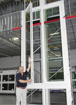 <p>
Größenvergleich: Rainer Taig öffnet ein über 4,50 m hohes Holzkastenfenster, das auf dem Funktionsprüfstand in der Produktionshalle steht. 
</p>