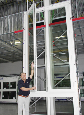 
Größenvergleich: Rainer Taig öffnet ein über 4,50 m hohes Holzkastenfenster, das auf dem Funktionsprüfstand in der Produktionshalle steht. 
